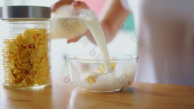 准备谷物早餐厨房表格关闭女人手倒牛奶